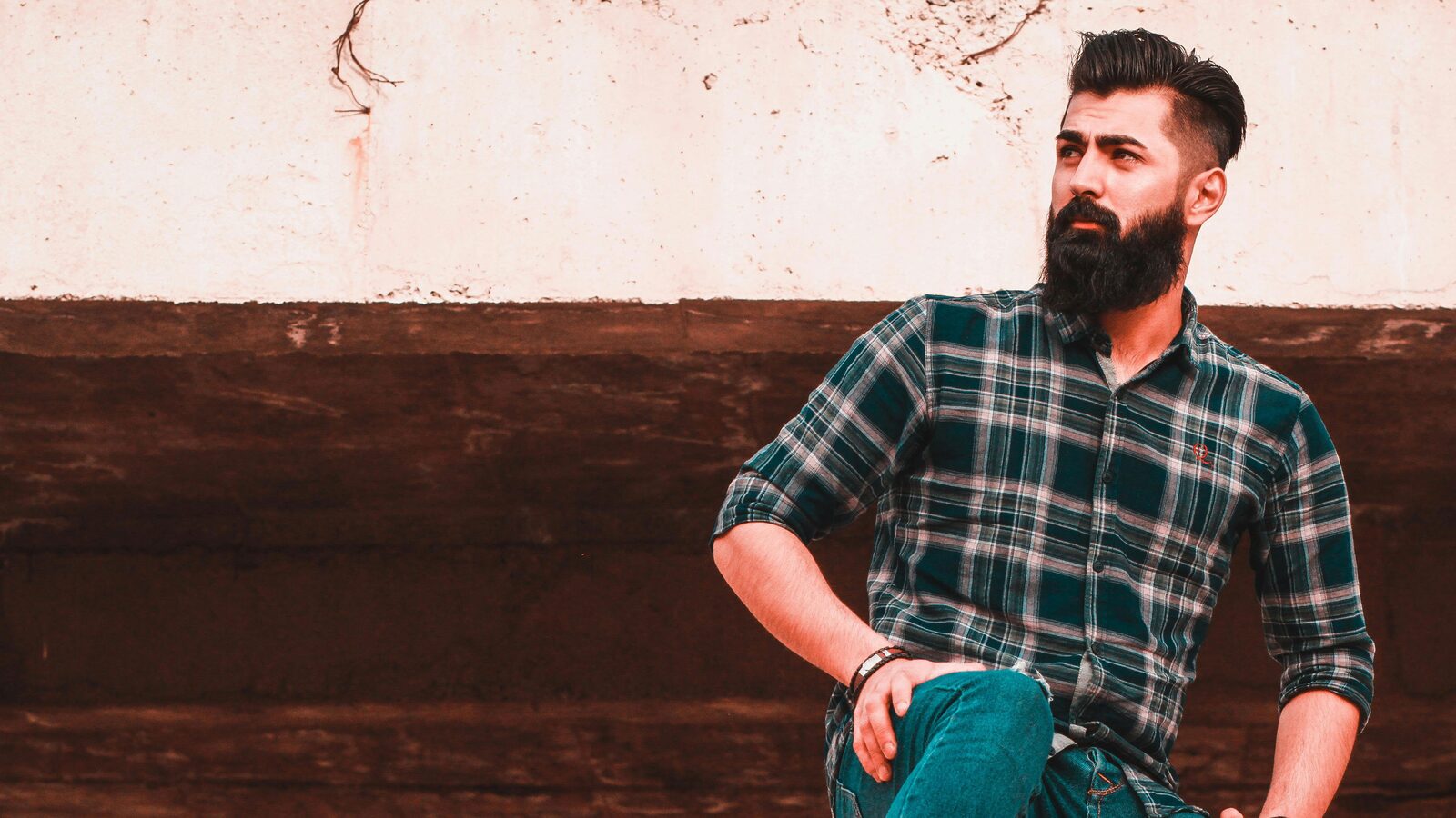 Bearded man leaning against a wall