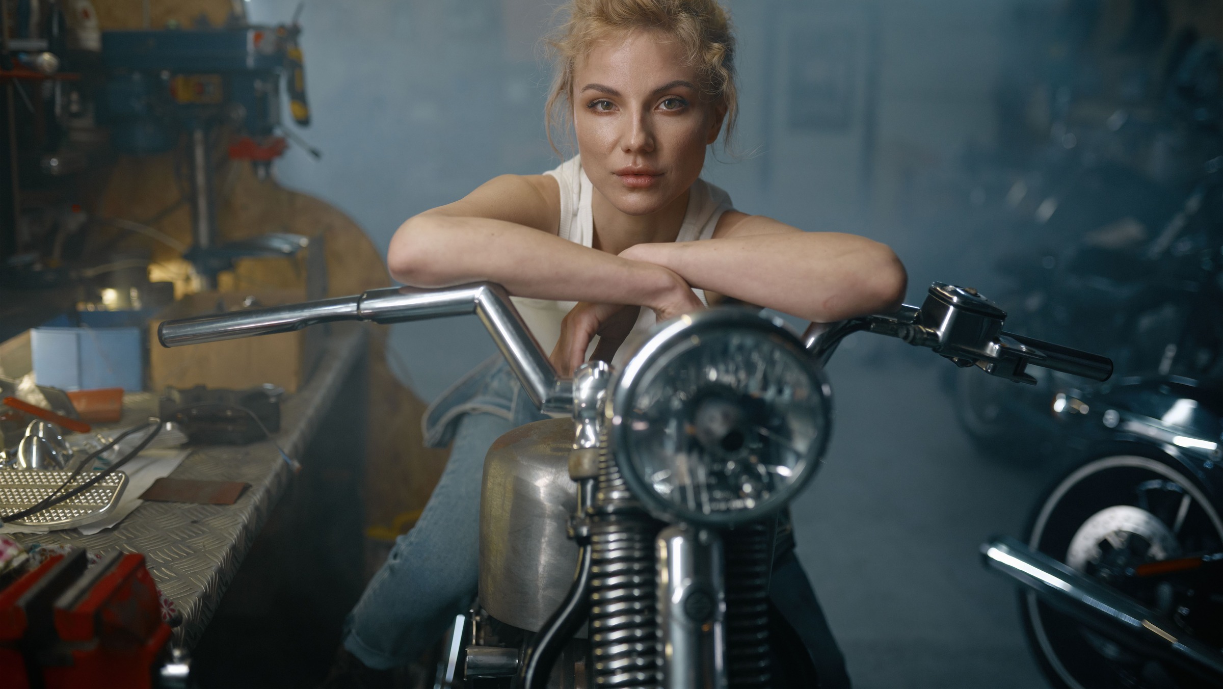 Woman leaning over a custom motorcycle in a workshop